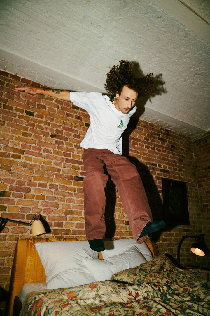 Young man in Jägermeister Merch is jumping on a bed