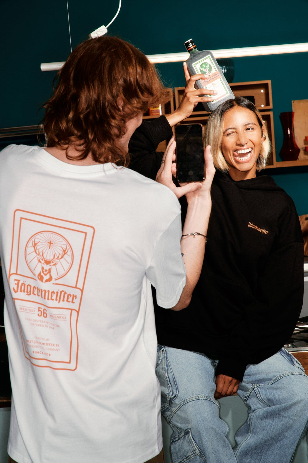 Két ember Jägermeister márkajelzéssel, laza környezetben.