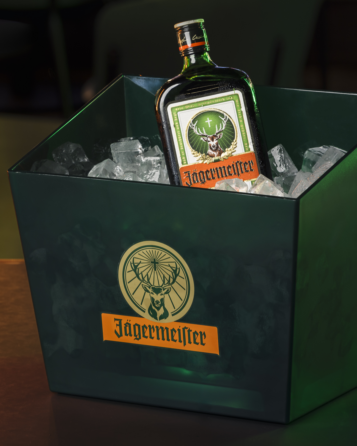 Jägermeister palack egy zöld jéghűtőben, látható logóval.
