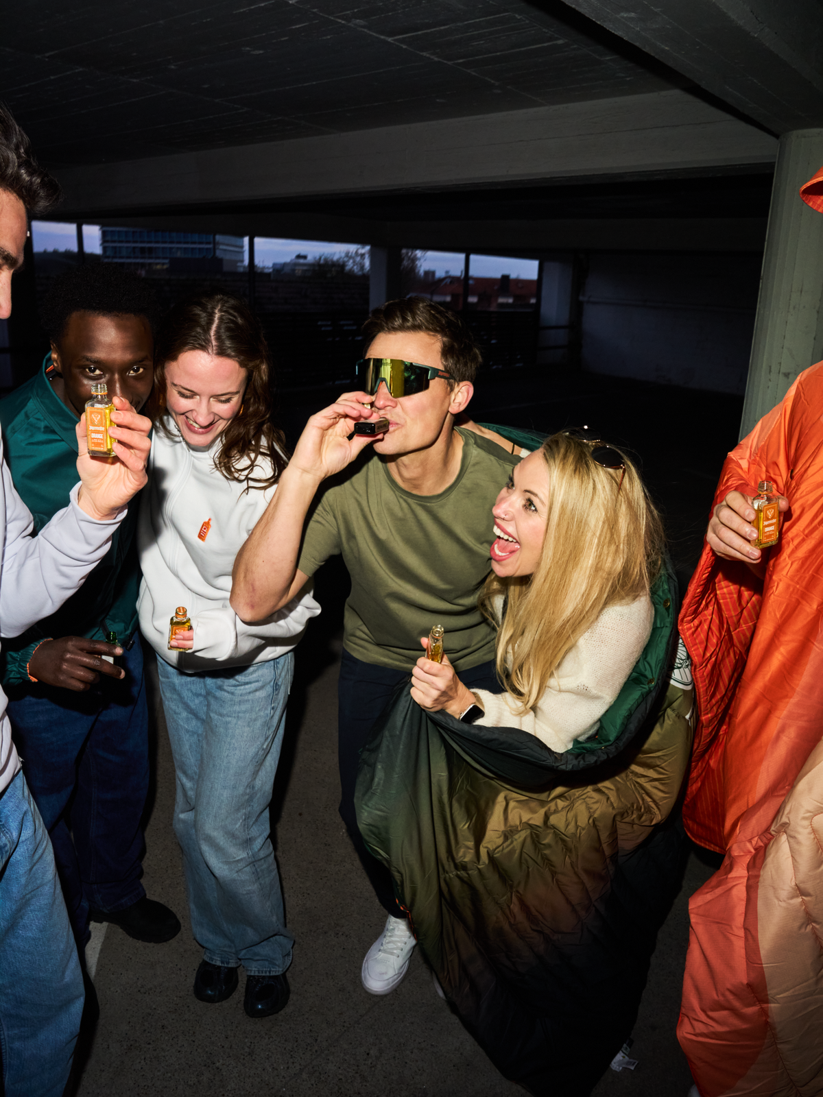 Csoportnyi ember Jägermeister shotokat iszik egy társas összejövetelen, köztük egy személy Jägermeister Fast Glasses szemüveget visel, tükröző lencsékkel és aerodinamikus kialakítással.