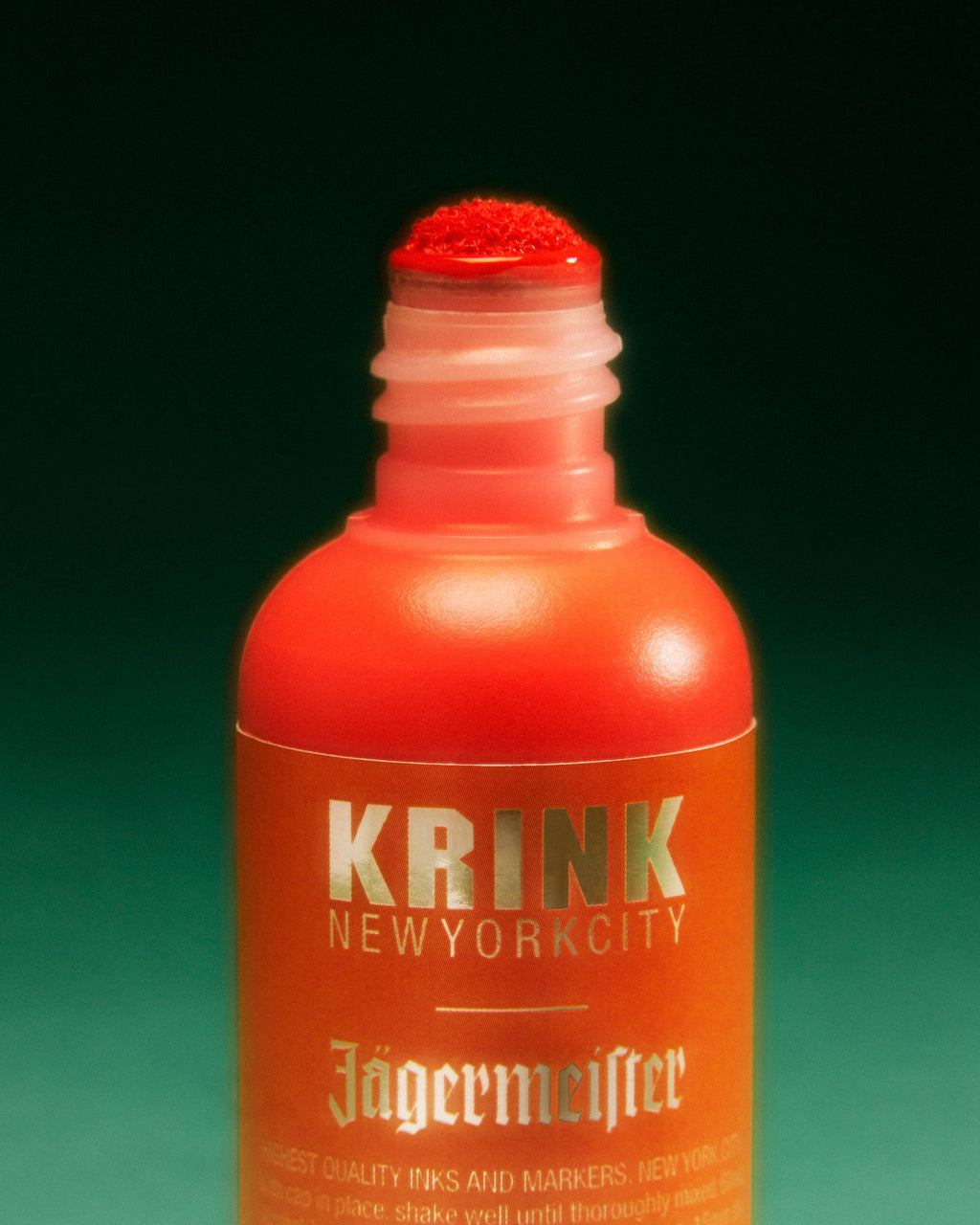 Narancssárga Krink marker Jägermeister márkajelzéssel, zöld háttéren