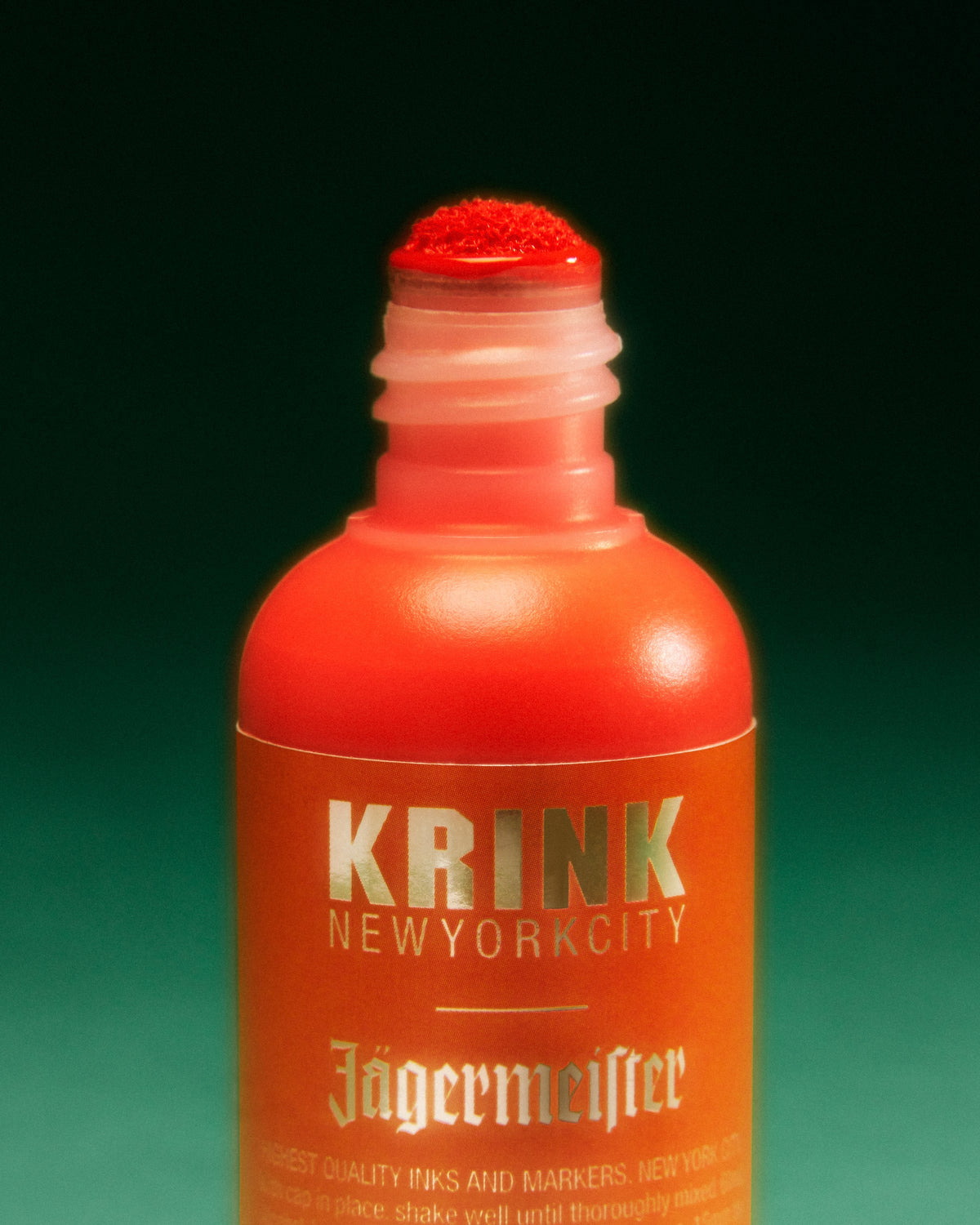 Narancssárga Krink marker Jägermeister márkajelzéssel, zöld háttéren