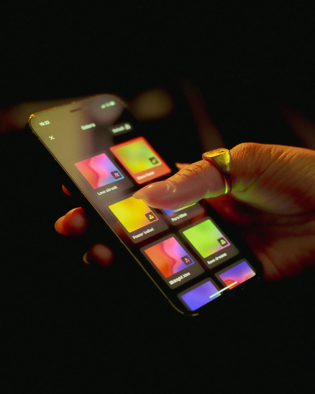 Kéz egy színes digitális eszközzel interakcióban sötét háttéren
