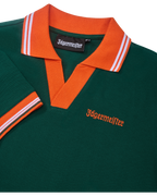 Zöld pólóruha narancssárga gallérral és szegéllyel, Jägermeister-márkajelzéssel.