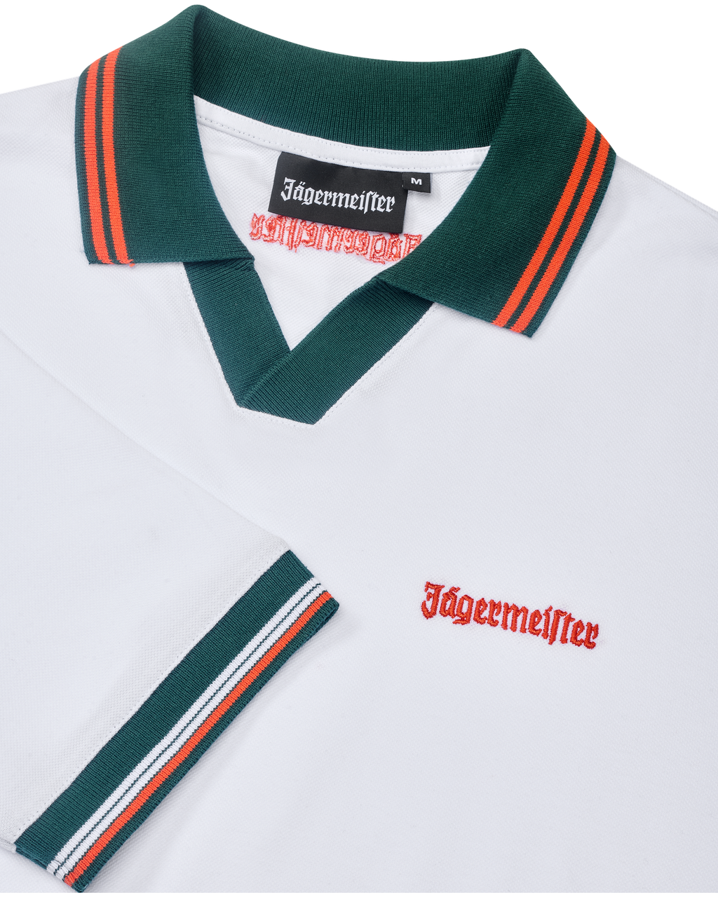 Fehér Jägermeister póló zöld gallérral és narancssárga szegéllyel, narancssárga Jägermeister-márkajelzéssel.