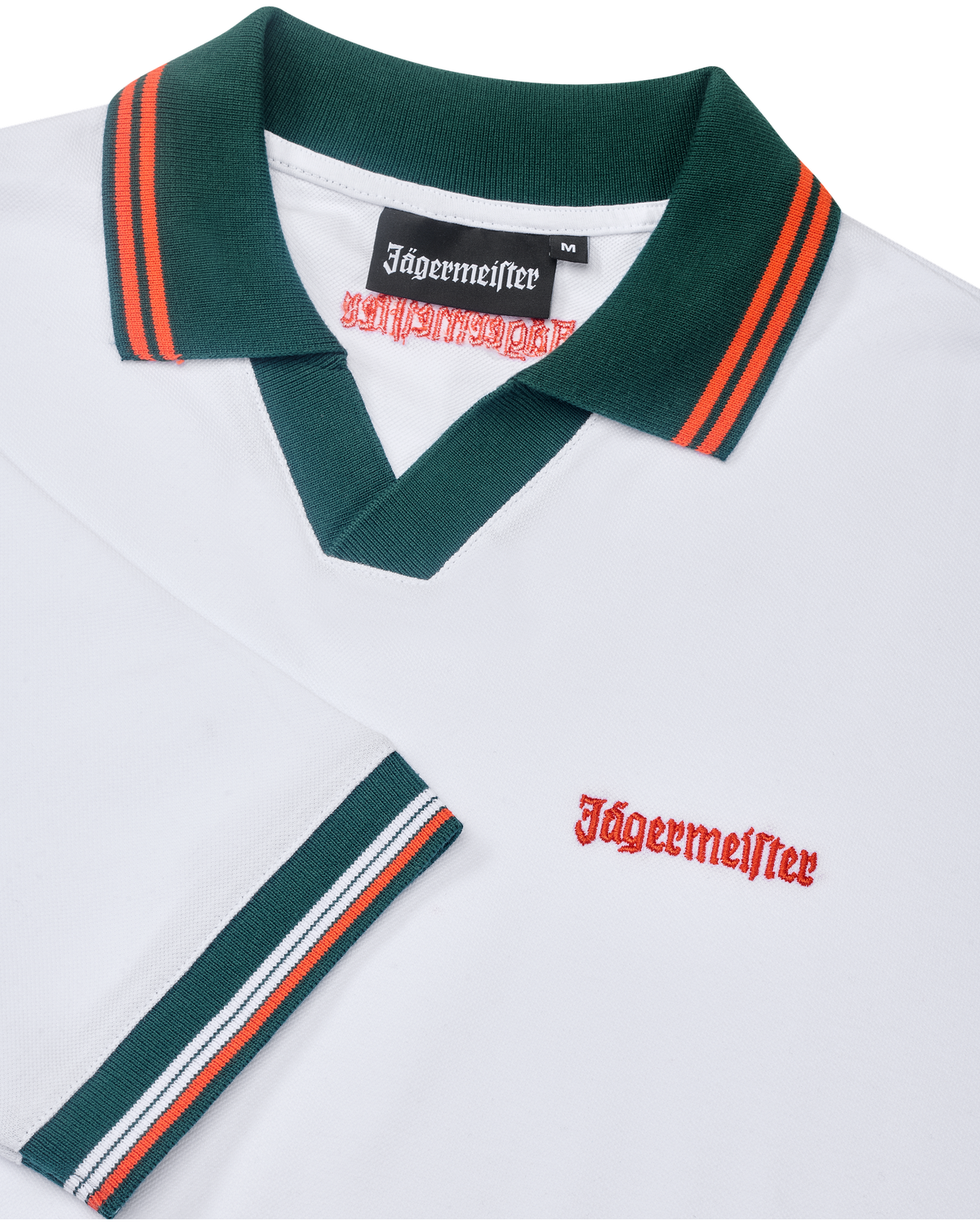 Fehér Jägermeister póló zöld gallérral és narancssárga szegéllyel, narancssárga Jägermeister-márkajelzéssel.
