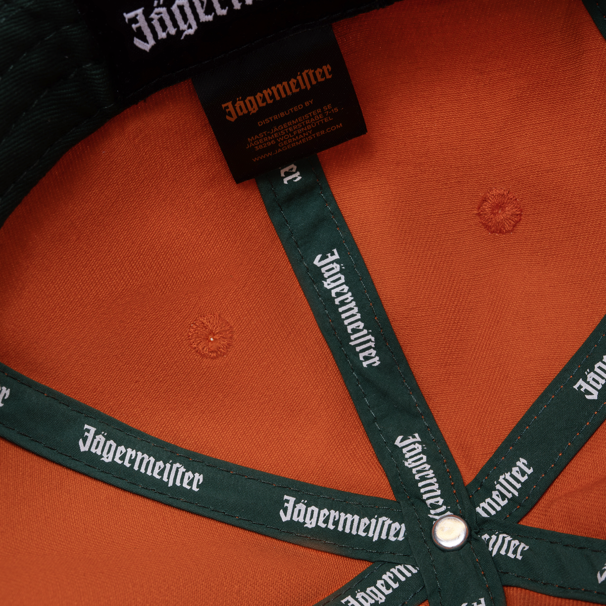 Narancssárga Jägermeister Racing sapka Jägermeister-márkajelzéssel a pánton és a címkén.