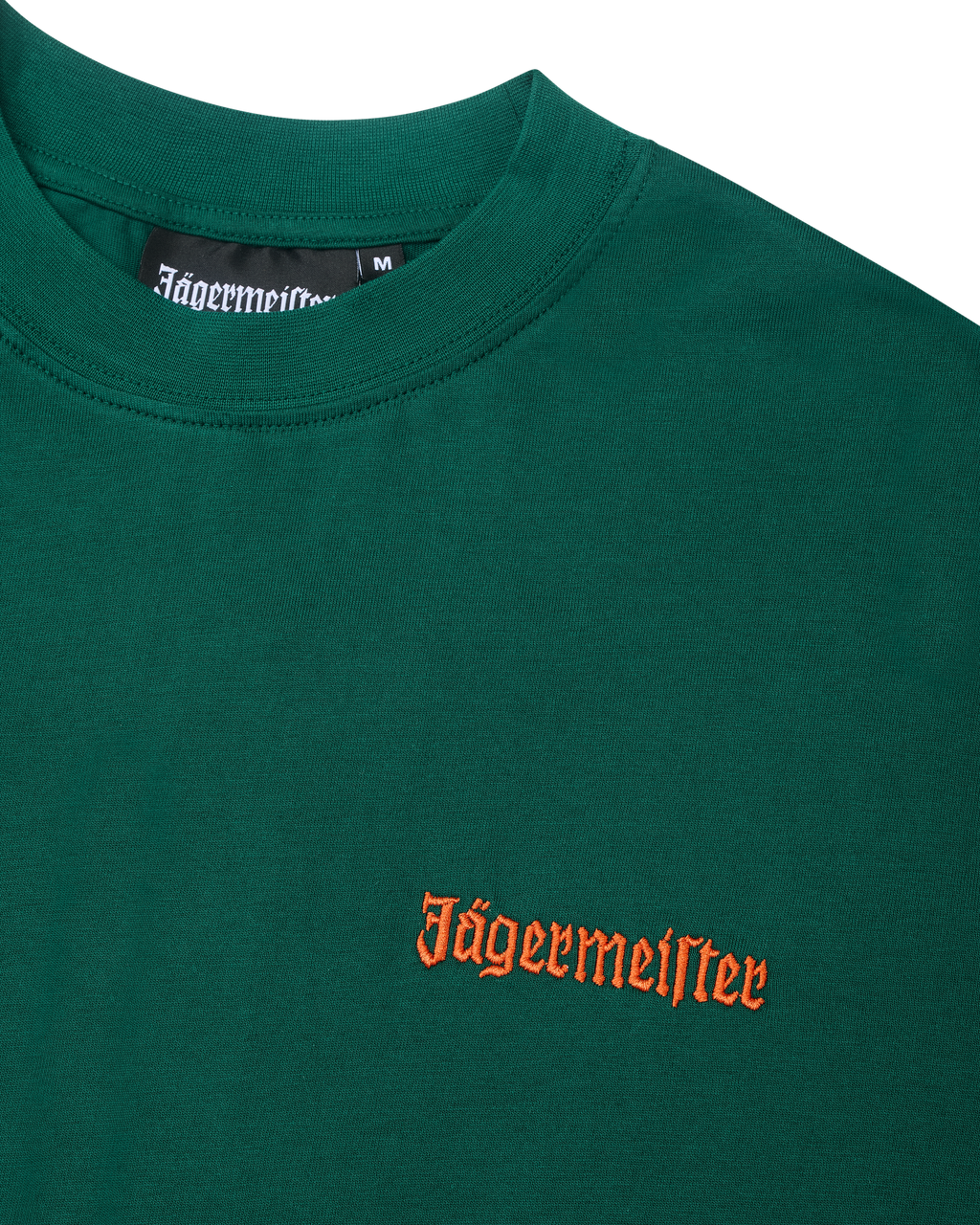 Zöld póló narancssárga Jägermeister logóval a mellkason.