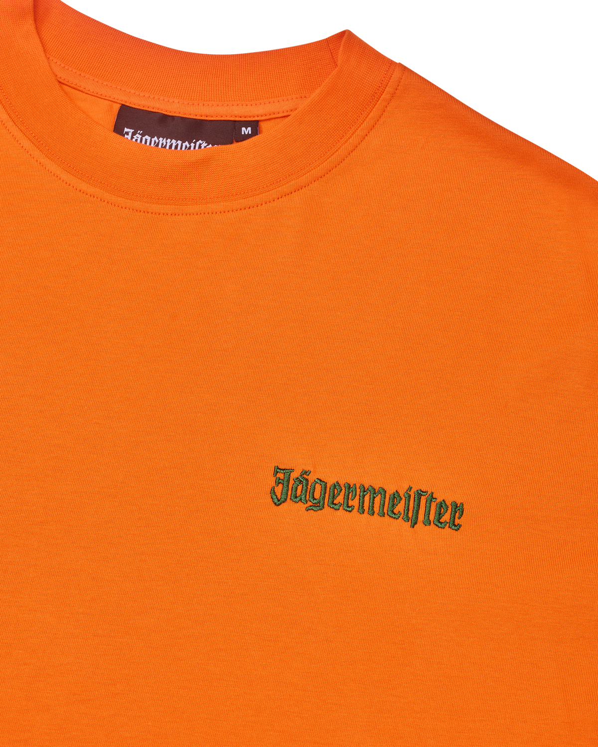 Narancssárga póló zöld Jägermeister logóval a mellkason.