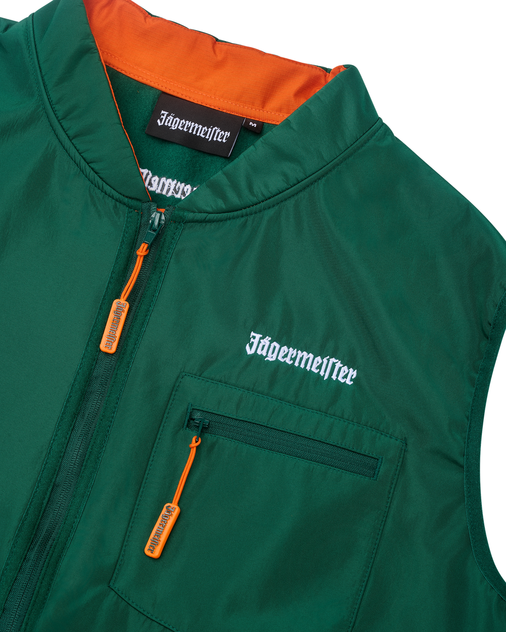 Zöld mellény narancssárga belső résszel és fehér Jägermeister márkajelzéssel.