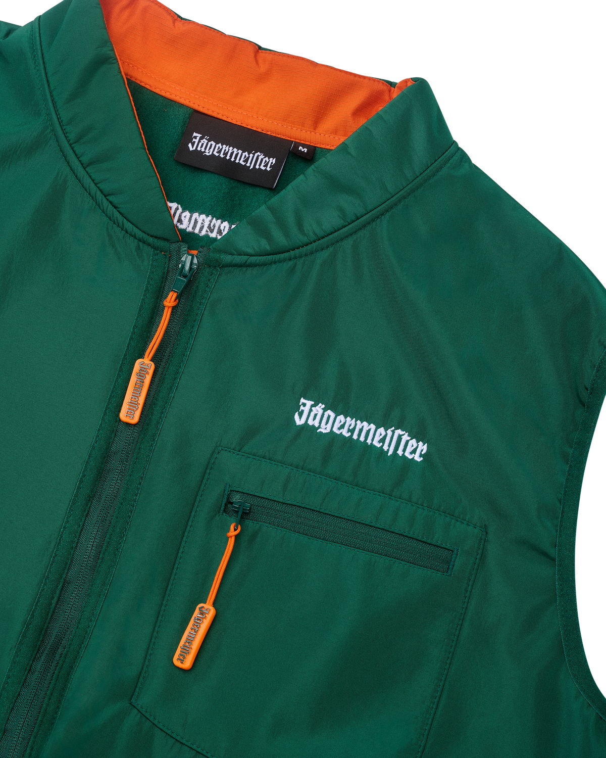 Zöld mellény narancssárga belső résszel és fehér Jägermeister márkajelzéssel.